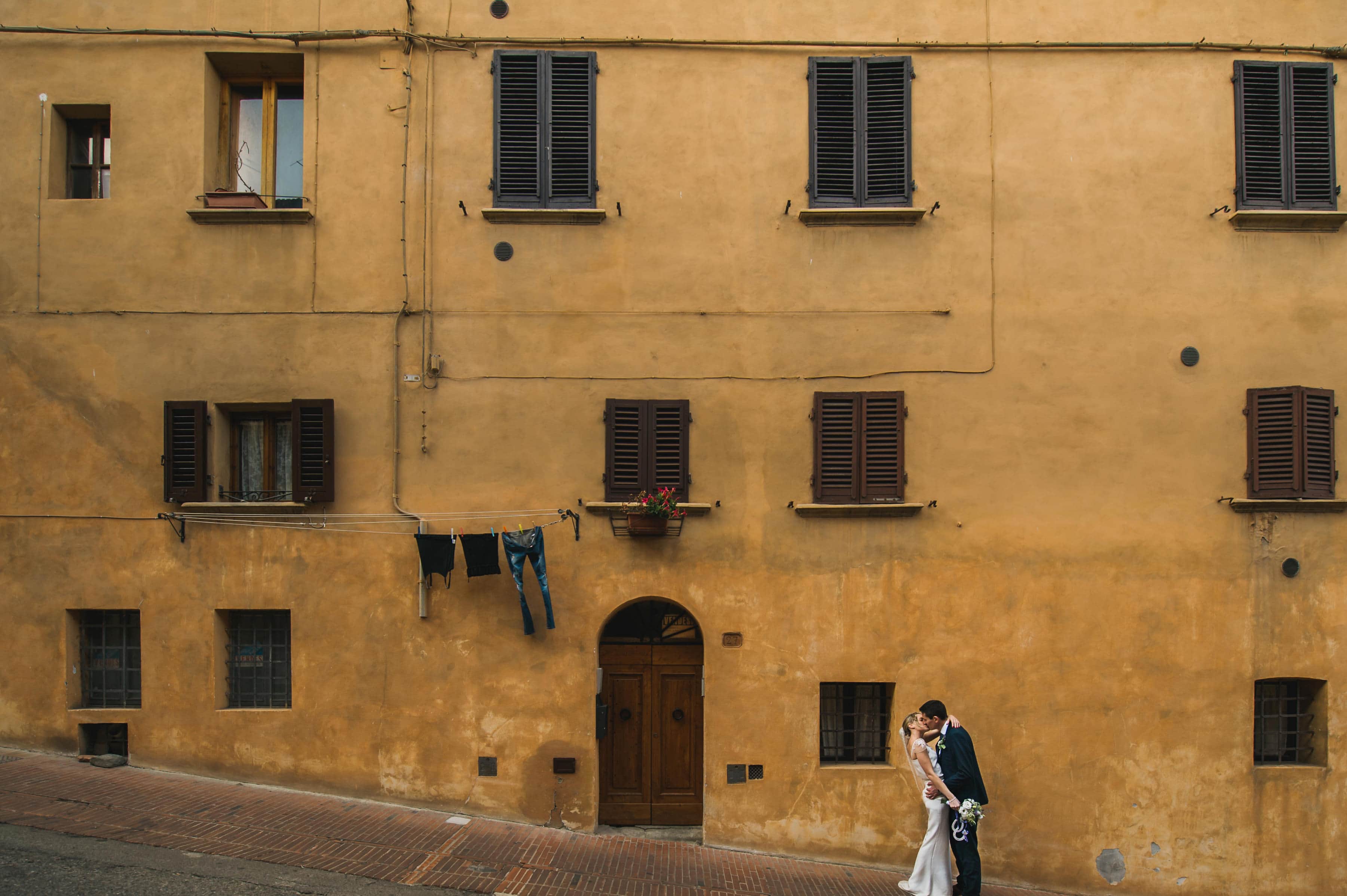 kissing on the street in San Gimignano after their wedding