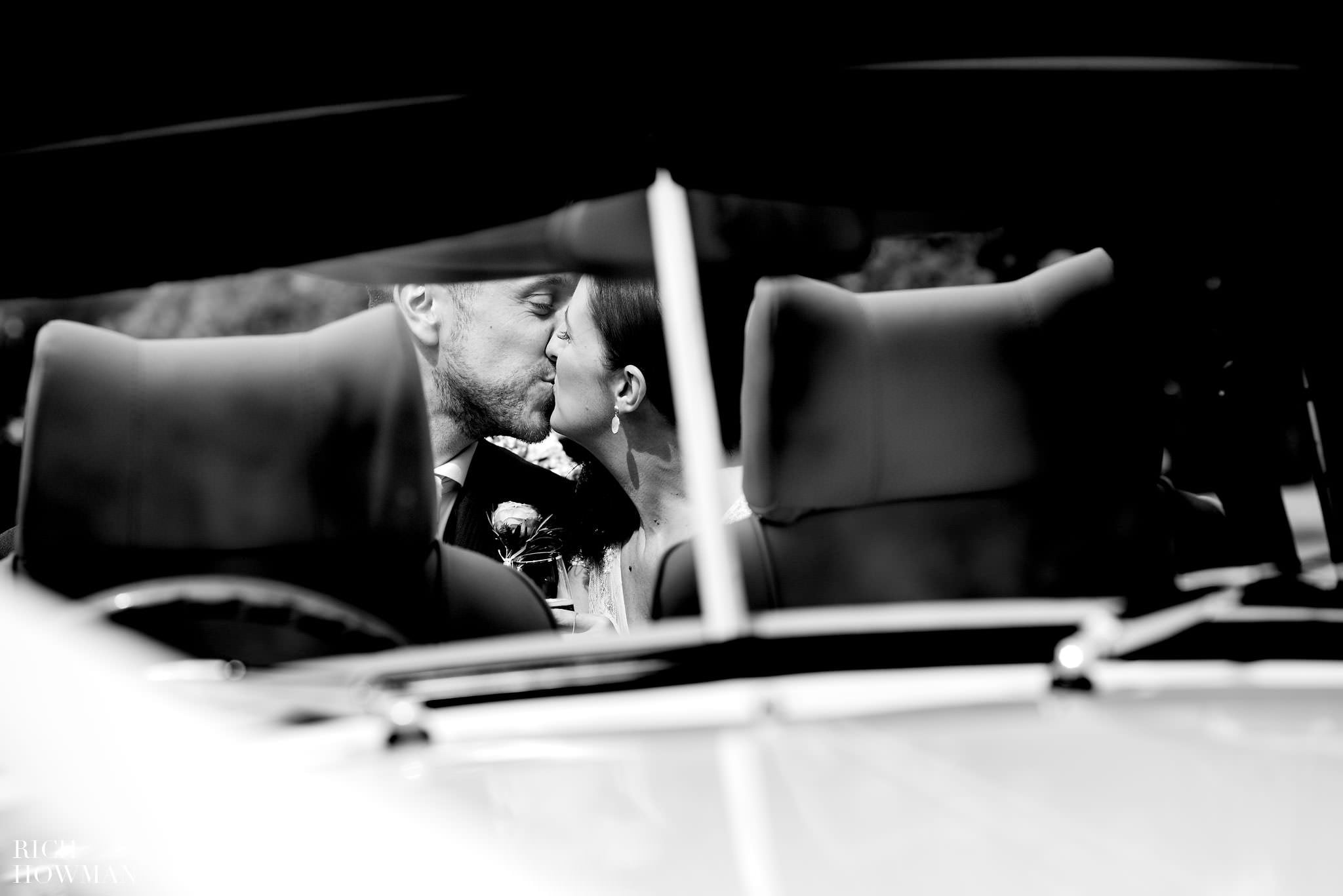 Reportage wedding photo off the married couple kissing through the car window